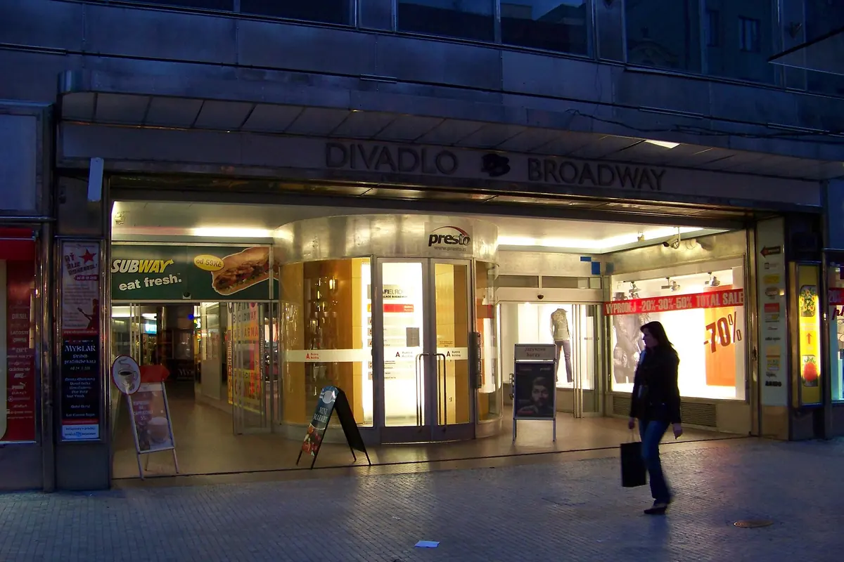 The Divadlo Broadway entrance on Na Příkopě in Prague, photographed in the evening, with lit shop windows below the theatre name