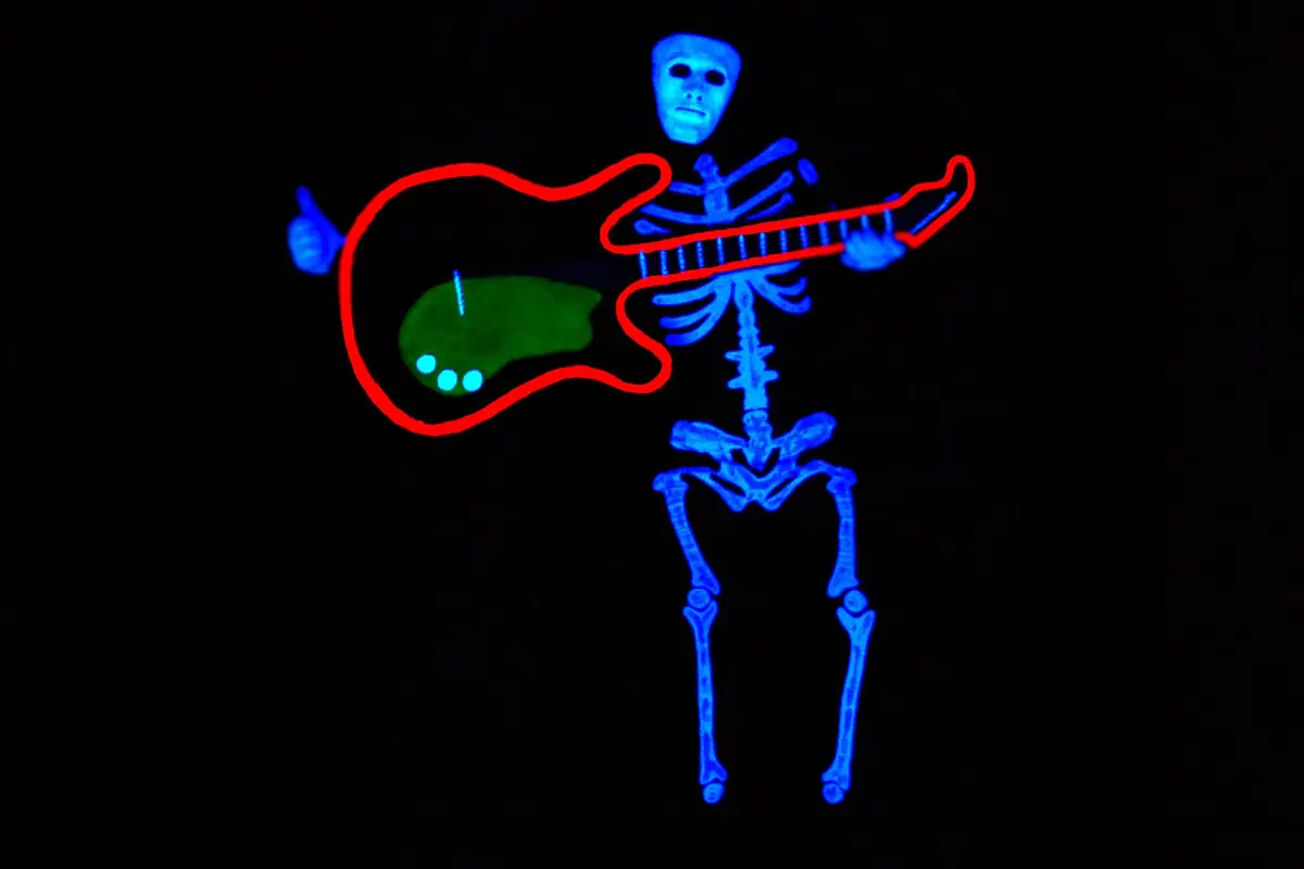 A glowing blue skeleton with a white mask plays a bright red outline guitar in the dark